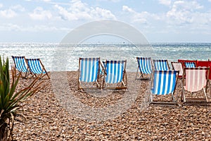 Colourful striped empty deck chairs on Brighton beach, England