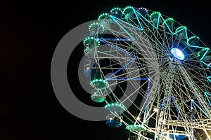 Colourful striped light illuminated spinning ferris wheel in motion moving at night