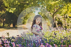 Colourful summer scene of cute runette young girl child enjoying free time in wild forest flowers field wearing stylish tiny dress