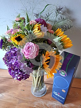 Colourful sunflowers, roses and hydrangas in a vase with champagne