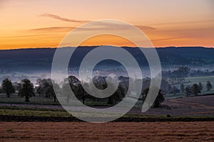 Colourful sunrise on a summer morning with a little fog on the ground and spectacular views over the Dutch hillside in Limburg