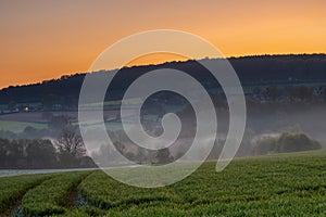 Colourful sunrise on a summer morning with a little fog on the ground and spectacular views over the Dutch hillside in Limburg