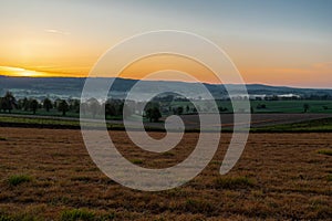 Colourful sunrise on a summer morning with a little fog on the ground and spectacular views over the Dutch hillside in Limburg