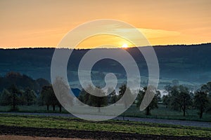 Colourful sunrise on a summer morning with a little fog on the ground and spectacular views over the Dutch hillside in Limburg