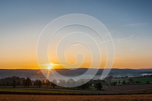 Colourful sunrise on a summer morning with a little fog on the ground and spectacular views over the Dutch hillside in Limburg