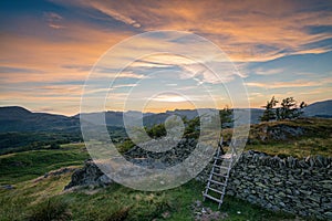 Colourful sunset across the beautiful Lake District by traditional stile