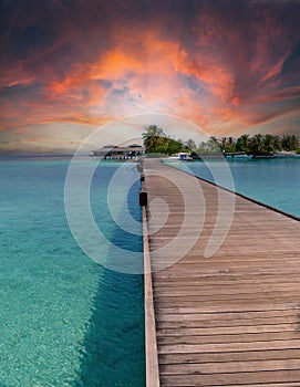 Colourful sunset at the maldive island with a boat and boardwalk