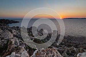 A colourful sunset over the cliffs of Paradis bay in Malta with a view on the Island of Gozo in the Mediterranean Sea.