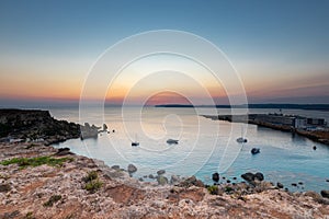 A colourful sunset over the cliffs of Paradis bay in Malta with a view on the Island of Gozo in the Mediterranean Sea.