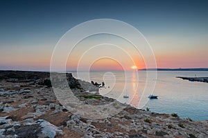 A colourful sunset over the cliffs of Paradis bay in Malta with a view on the Island of Gozo in the Mediterranean Sea.