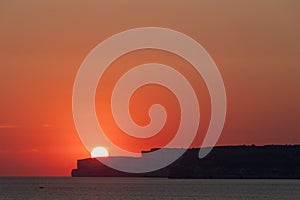 A colourful sunset over the cliffs of Paradis bay in Malta with a view on the Island of Gozo in the Mediterranean Sea