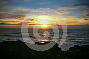 Colourful sunset over the sea at Punakaiki Pancake Rocks and Blowholes, New Zealand