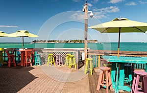 Colourful tables and chairs on a terrace along the ocean, holiday concept