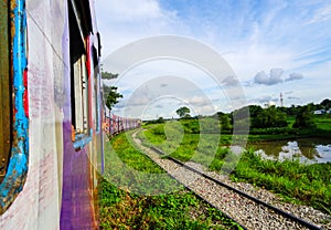 A colourful train going around a bend with grassy banks surround