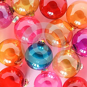 Colourful translucent glass Christmas baubles on pink background. Creative decoration.