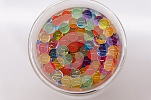 Colourful water beads balls on a circle drinking glass on a white background