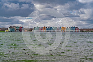 Colourful wooden lakeside houses De Rietplas. Modern residential architecture in Houten, The Netherlands