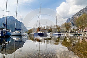 Colourful yachts docked at marina of Lecco town on spring day. Picturesque waterfront of Lecco located between famous Lake Como