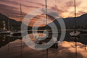 Colourful yachts docked at marina of Lecco town on spring sunset. Picturesque waterfront of Lecco located between famous Lake Como