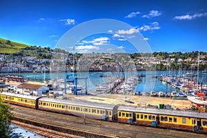 Colourful yellow train carriages by marina with boats in HDR