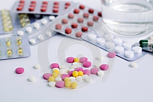 Colours pills on white background with glass of water