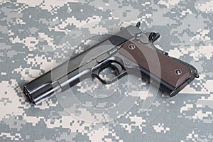 Colt 1911 handgun on camouflage uniform