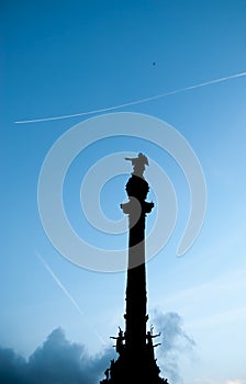 Columbus monument on blue sky background and Jet plane. Barcelona