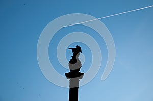 Columbus monument on blue sky background and Jet plane. Barcelona