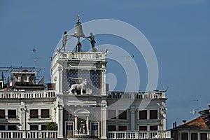 Column with lion of St Mark, symbol of imperial Venice, Zodiac clock Tower and Mother of God in San Marco`s square on the buildin