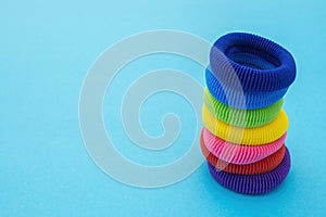 Column of multicolored scrunchies, elastic hair ties, cotton hair ponytail holders, seamless hair bands on blue backdrop