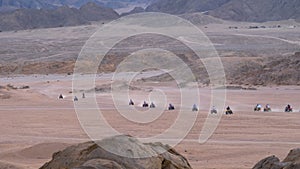 Column of a Quad Bike Rides through the Desert in Egypt on backdrop of Mountains. Driving ATVs.