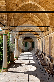 Columned portico with Stone Pillars and wooden Benches in Mosqu