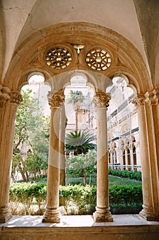 Columns and arches of a courtyard with a garden of the Dominican monastery in Dubrovnik, Croatia.