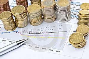 Columns of coins and pen on business chart