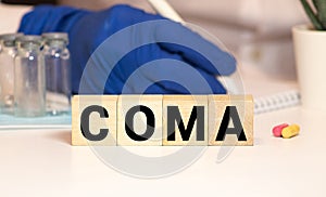Coma - word from wooden blocks with letters, the complete absence of wakefulness unconsciousness concept, random letters around, photo