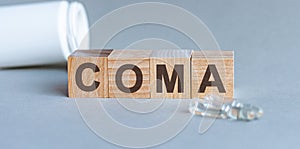 COMA is a word written in black letters on wooden cubes