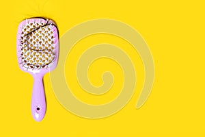 Comb brush with tufts of fallen hair when combing on a yellow background