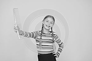 Comb not just for blonde. Happy child hold blue comb yellow background. Little girl smile with plastic hair comb. Small