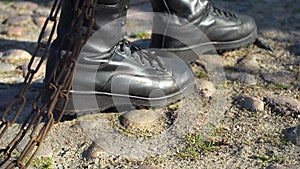 Combat boots tugging chain prison concept