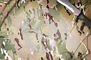 Combat knife on military camouflage fabric background