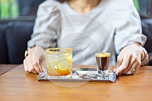 A combination between fresh Coffee, Lemon, Orange Soda on the stainless plate on wood table in front of blur woman in Coffee cafe