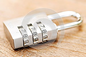 Combination padlock close up with chrome numbers on wooden backg