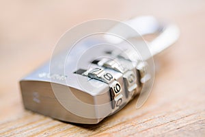 Combination padlock close up with chrome numbers on wooden backg