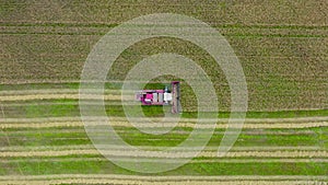 Combine drives slowly across field. Working. Top view