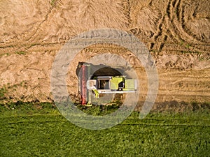 Combine harvester - Aerial view of modern combine harvester at the harvesting the wheat on the golden wheat field in the summer