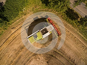 Combine harvester - Aerial view of modern combine harvester at the harvesting the wheat on the golden wheat field in the summer