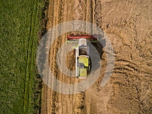 Combine harvester - Aerial view of modern combine harvester at the harvesting the wheat on the golden wheat field in the summer