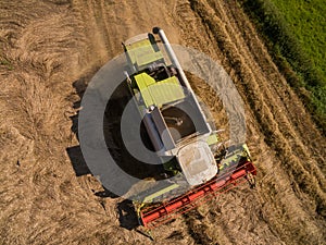 Combine harvester - Aerial view of modern combine harvester at the harvesting the wheat on the golden wheat field in the summer