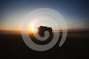 Combine harvester at gold light in agriculture fields with wheat