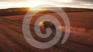 Combine harvester harvests wheat in the field at sunset in autumn in Russia. view from a height of equipment and field